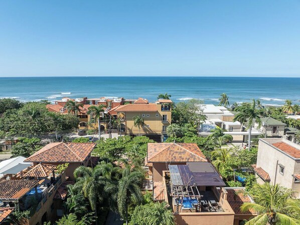 A coastal residential area with houses featuring red-tiled roofs and palm trees. - Luxury 3BR 3.5 Bath Across the Street from Beach with 2 Private Pools (Playa Langosta)