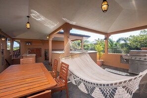 A patio area with a wooden table, chairs, a hammock, a grill, and a sink. - Luxury 3BR 3.5 Bath Across the Street from Beach with 2 Private Pools (Playa Langosta)