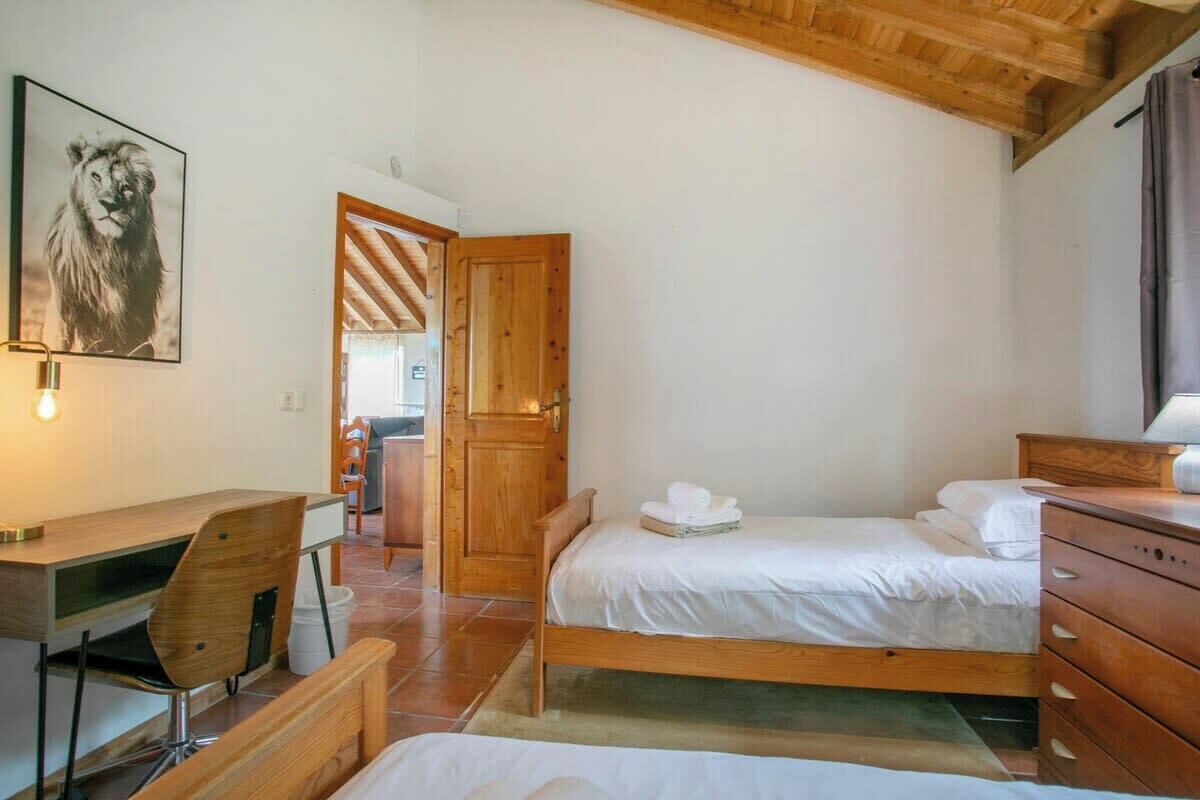 Quarto com duas camas, uma escrivaninha e uma cadeira.