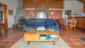 Un salon chaleureux avec une cheminée en pierre, un canapé bleu, une table à manger en bois et une bibliothèque.