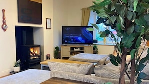 Un salon chaleureux avec une cheminée, un téléviseur à écran plat et des sièges confortables.