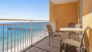 Un balcón con vista al océano y un muelle, amoblado con una mesa y sillas.