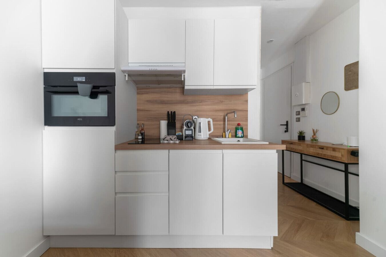 A modern kitchen with white cabinets, a wooden countertop, and a built-in oven.