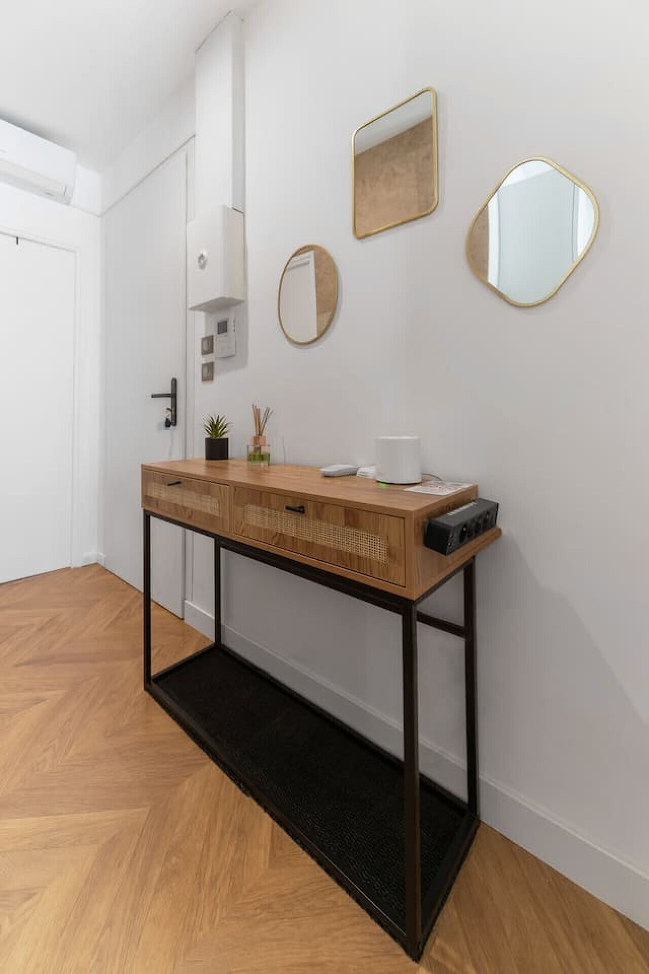 A wooden console table with a black base, a white cup, and a small plant on top.