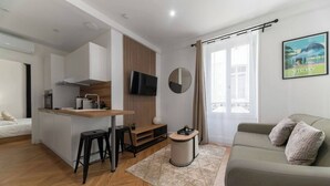 A modern apartment with a kitchenette, a dining area, a sofa, and a large window with curtains. - Chez Juliette - 4 rue de Serbie - Vichy (Vichy)