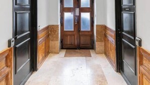 A hallway with two black doors, a double door with glass panels, and a tiled floor. - Chez Juliette - 4 rue de Serbie - Vichy (Vichy)