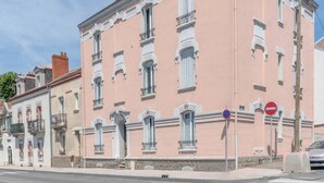 Ein rosafarbenes Gebäude im klassischen Stil mit zahlreichen Fenstern und einer symmetrischen Fassade.