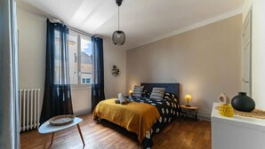 Ein Schlafzimmer mit Bett, einem kleinen Tisch, einer Lampe und einer Heizung.