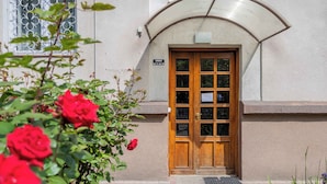A building entrance with a wooden door, a sign above the door, and a window with metal bars. - Bright Apartment | Place to Work | Close to the Royal Baths (Warszawa)