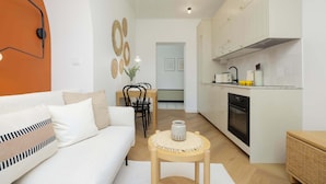 A modern kitchen with white cabinets, a black oven, and a dining area with a table and chairs. - Bright Apartment | Place to Work | Close to the Royal Baths (Warszawa)