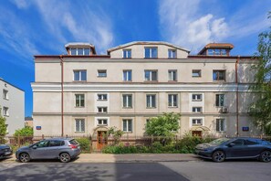 A multi-story residential building with a flat facade, multiple windows, and a gated entrance.
