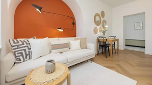 A modern living room with a white sofa, a round coffee table, and a dining area with a wooden table and chairs. - Bright Apartment | Place to Work | Close to the Royal Baths (Warszawa)
