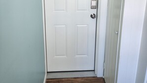 A white door with a keypad lock, a wooden floor, and a light blue wall. - G St Inn Unit 5 Lovely 1-bedroom apartment in Hampton with AC, WiFi (Hampton)