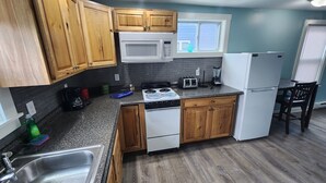 A compact kitchen with wooden cabinets, a microwave, a stove, and a refrigerator. - G St Inn Unit 5 Lovely 1-bedroom apartment in Hampton with AC, WiFi (Hampton)