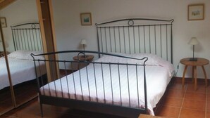 A room with two metal-framed beds, a small wooden table, and a lamp.