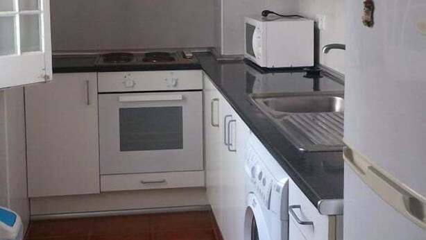 A compact kitchen with a stove, oven, microwave, and a washing machine.