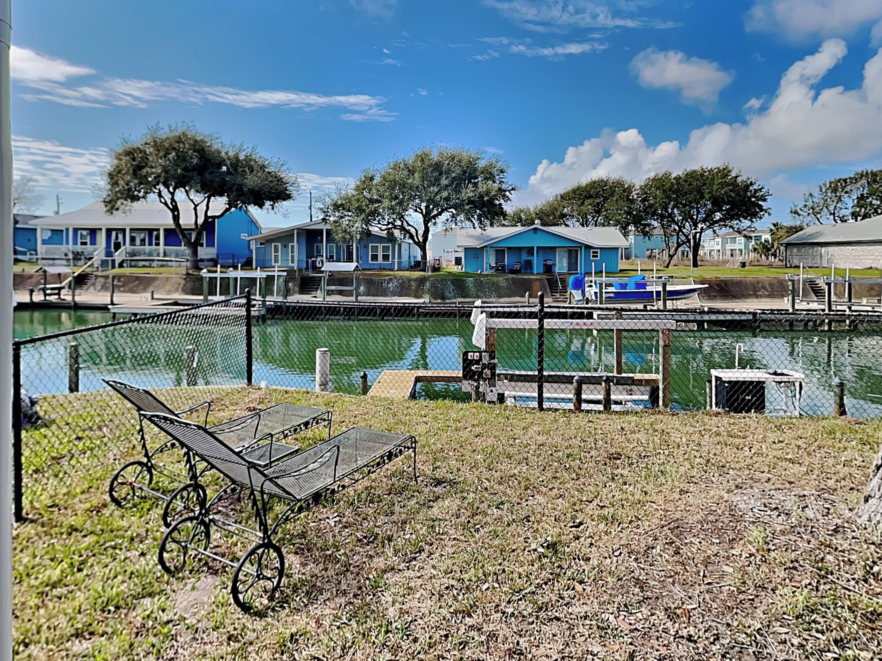 A lakeside view with a dock, a small boat, and a row of blue houses.