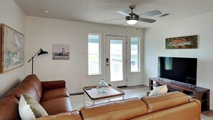 Ein Wohnzimmer mit einem braunen Ledersofa, einem Couchtisch, einem Fernseher und einem Deckenventilator.