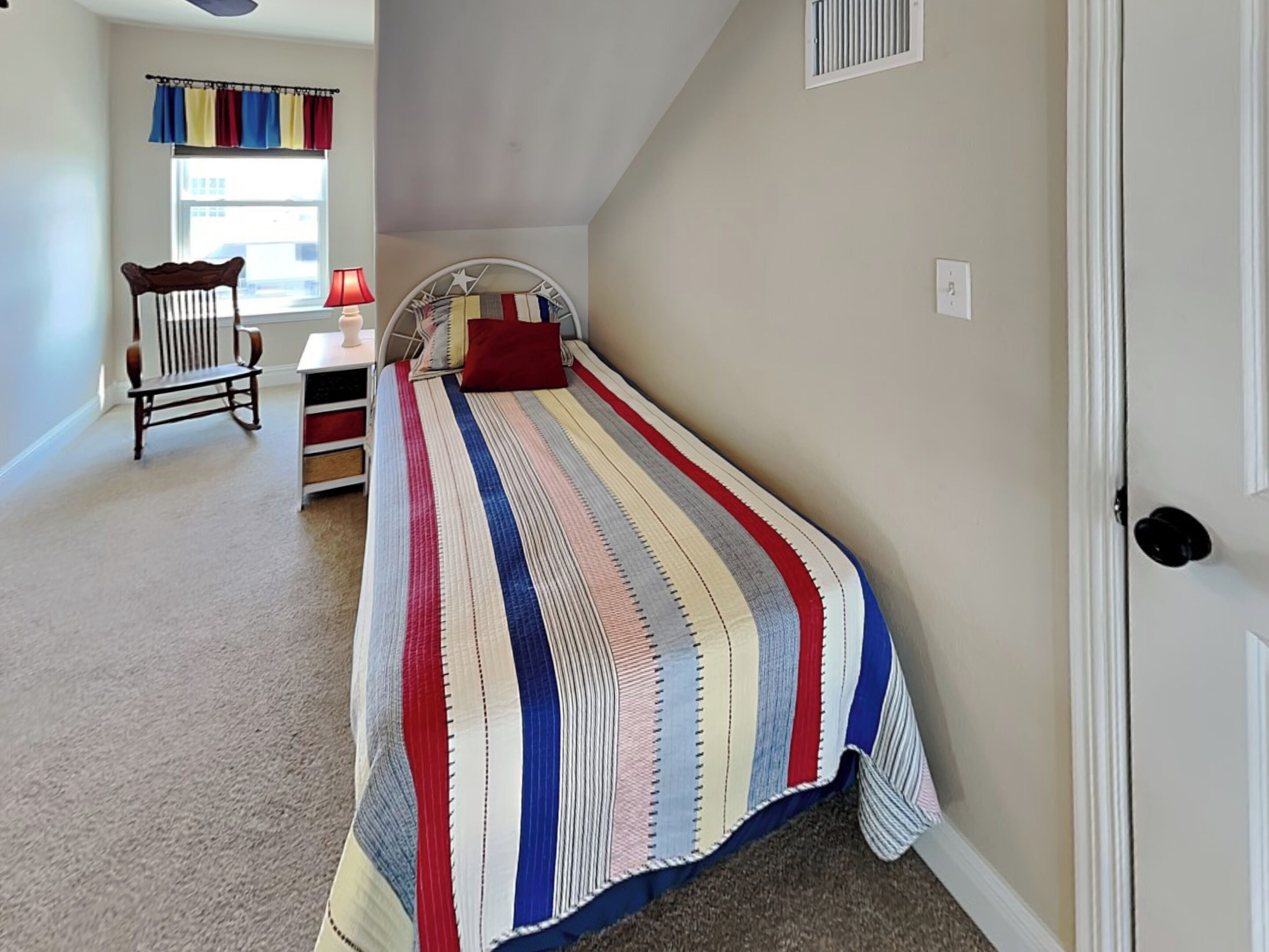 A bedroom with a bed, a chair, a desk, and a window.