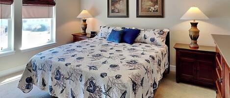 A bedroom with a large bed, two wall-mounted lamps, and two framed pictures.