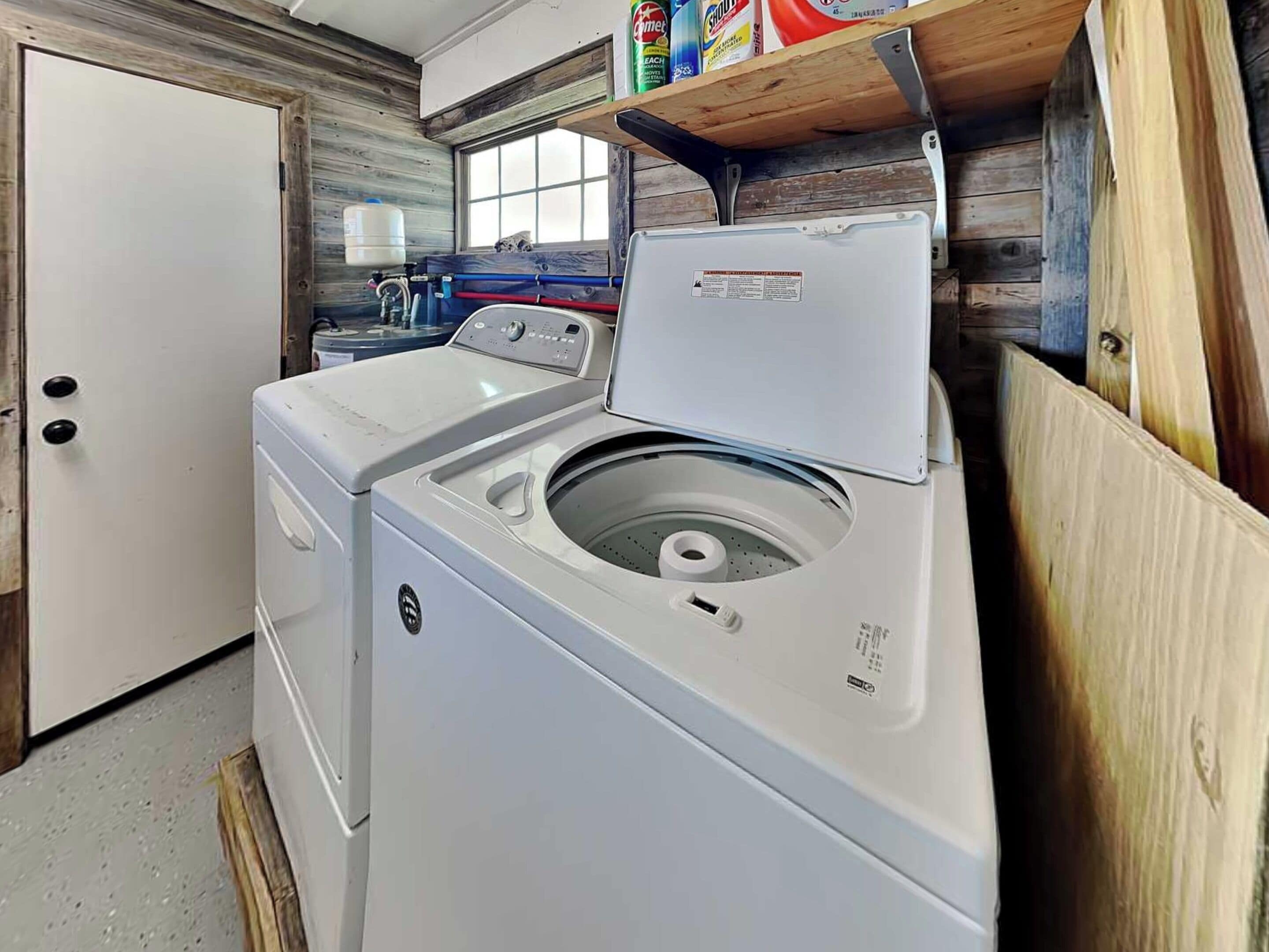 A laundry room with a front-loading washer and dryer, a window, and a shelf with cleaning supplies.