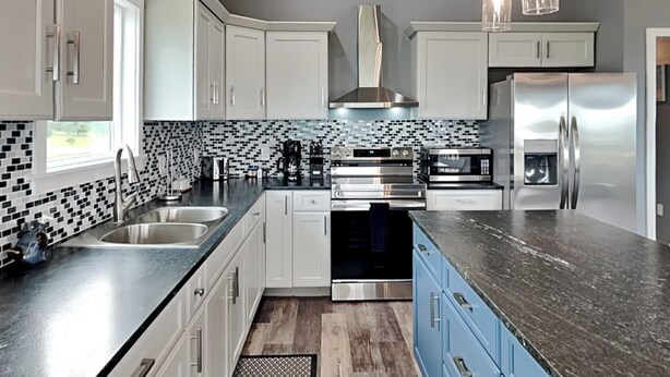 A modern kitchen with white cabinets, a black countertop, and stainless steel appliances. - Fish Tales by Miss Kitty’s (Rockport)