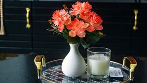 Eine Fernbedienung, ein Glas Milch und eine Blumenvase auf einer Ablagefläche.