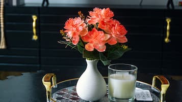 Une télécommande, un verre de lait et un vase rempli de fleurs, le tout posé sur un plateau.