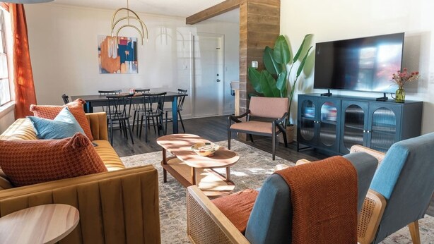 A modern living room with a sofa set, a dining table, and a TV.