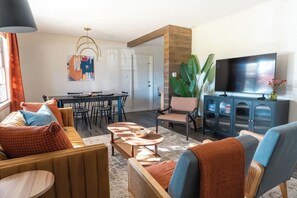 Una sala de estar moderna con un conjunto de sofás, una mesa de comedor y un televisor.