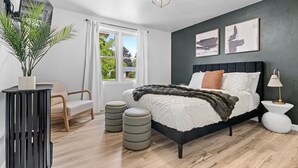 Un dormitorio moderno con una cama, una silla, una planta y una ventana.