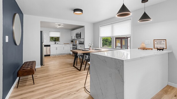 Una cocina moderna con una isla de mármol, iluminación colgante y vistas al exterior.