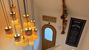 Un escalier avec une main courante en bois et une balustrade blanche, menant à une porte dotée d’une vitre en verre dépoli.
