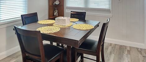A dining area with a wooden table, four chairs, and two pendant lights.