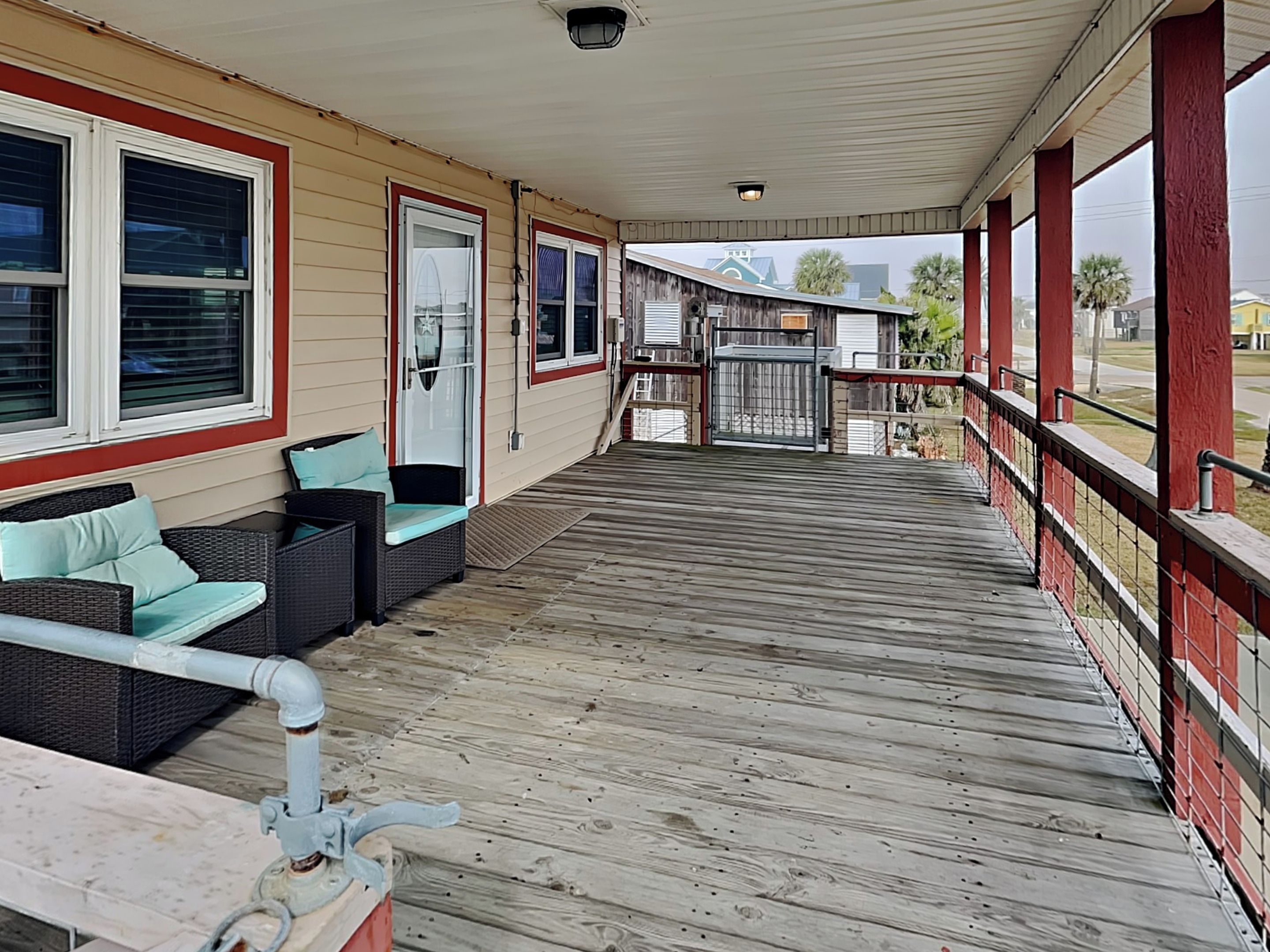 A covered porch with outdoor seating, a gated entrance, and a view of the surrounding area.