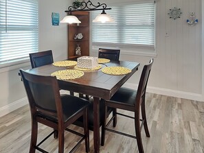 A dining area with a wooden table, four chairs, and two pendant lights.