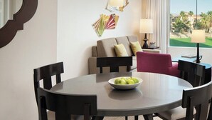 A dining area with a round table, chairs, a bowl of fruit, a sofa, and a lamp. - 2-bedroom condo in marvelous Palm Desert with AC, WiFi, fitness room (Palm Desert)