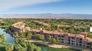 A resort with multiple buildings, a lake, and mountains in the background. - 2-bedroom condo in marvelous Palm Desert with AC, WiFi, fitness room (Palm Desert)