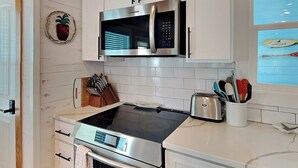 A modern kitchen with white cabinets, a stainless steel microwave, a toaster, and a built-in oven.