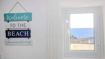 Una pared con un cartel que dice 'Welcome to the Beach' y una ventana con vista al mar.