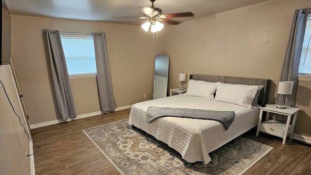 A bedroom with a bed, nightstands, a ceiling fan, and a rug. - Modern 4 Bedroom with King bed (Lubbock)