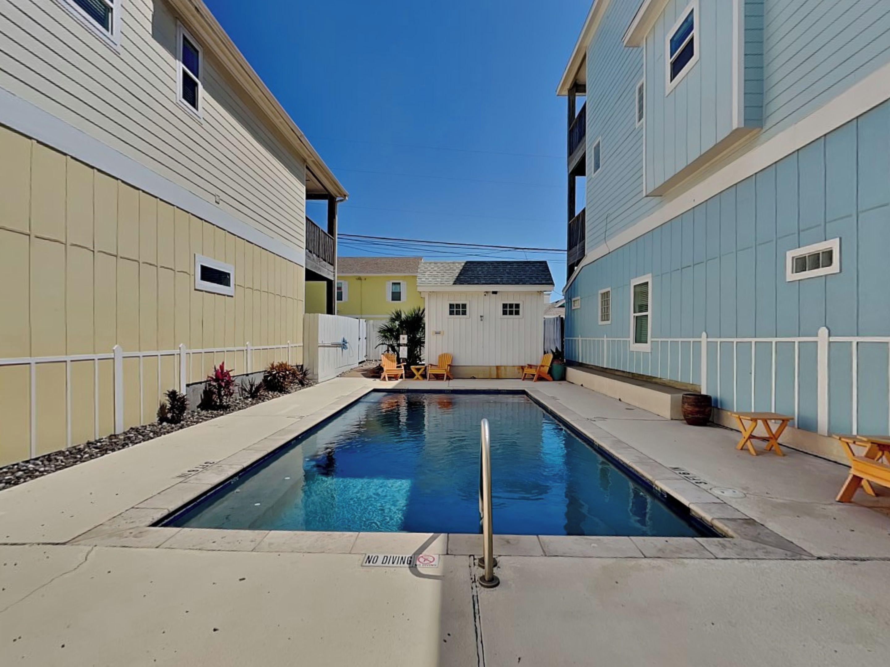 A swimming pool surrounded by buildings, with a 'NO DIVING' sign visible.