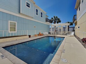 A swimming pool area with lounge chairs and a pergola. - Reel Nauti by Silver Sands Vacation Rentals (Port Aransas)