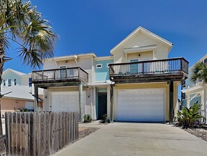 A two-story house with a garage, a balcony, and a driveway. - Reel Nauti by Silver Sands Vacation Rentals (Port Aransas)
