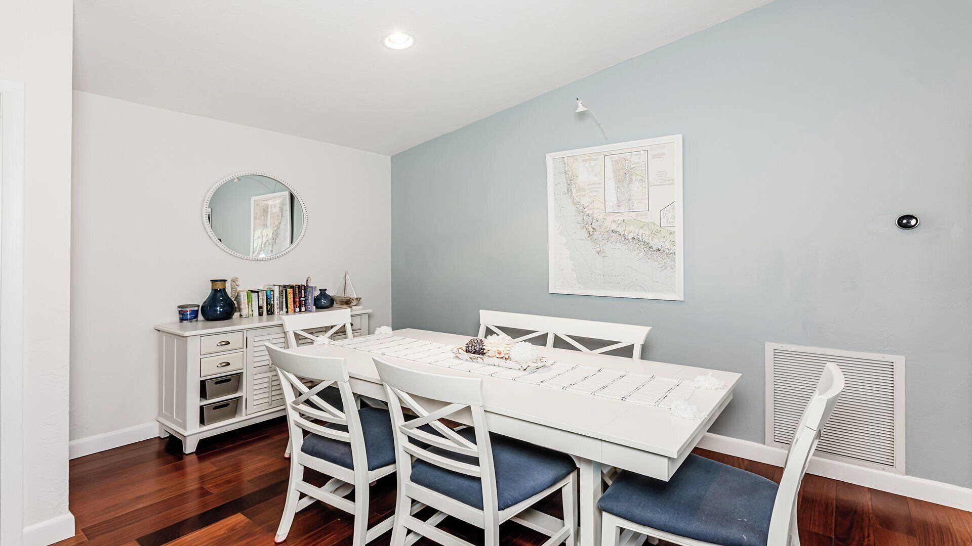 A dining area with a white table, blue chairs, a white cabinet, and a map on the wall.