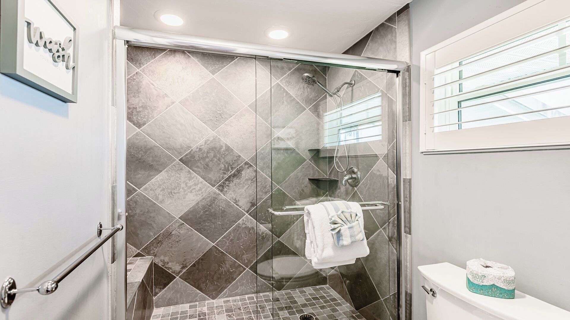 Un baño moderno con ducha, inodoro y cabina de ducha con mampara de vidrio.
