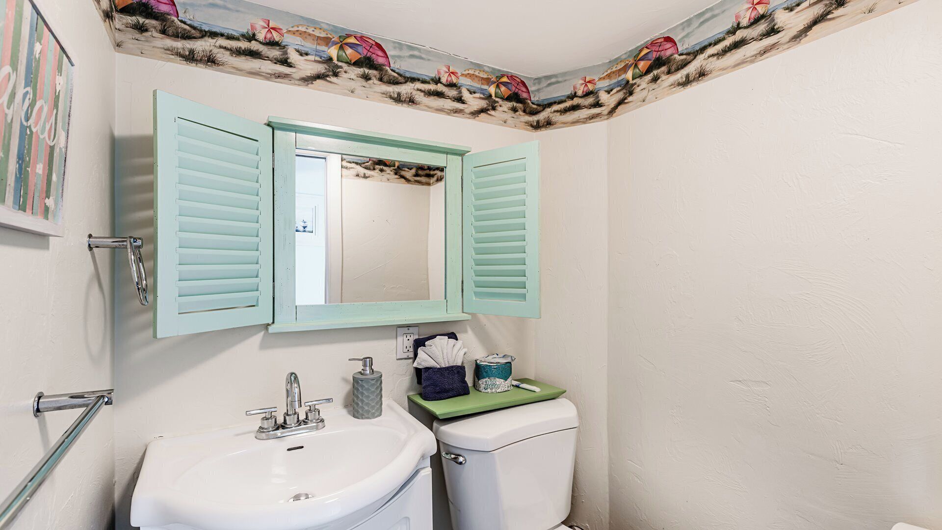 A bathroom with a white sink, a toilet, and a mirror with light blue shutters.