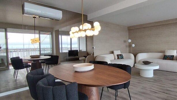 A modern living room with a round wooden table, two sofas, and a dining area.