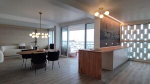 A modern living room with a dining area, large windows, and a city view.