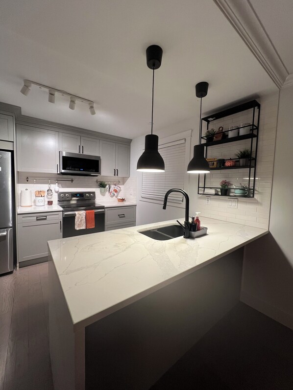 Een koelkast met diepvriezer, een microgolfoven, een oven, een kookplaat